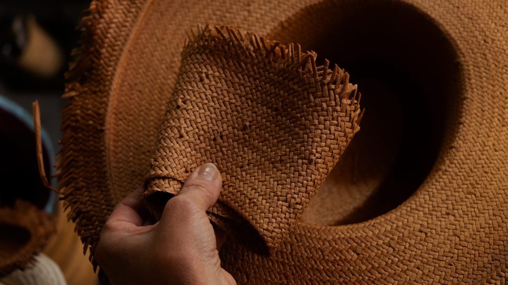Detalle del trenzado de paja de un sombrero artesanal en fabricación.